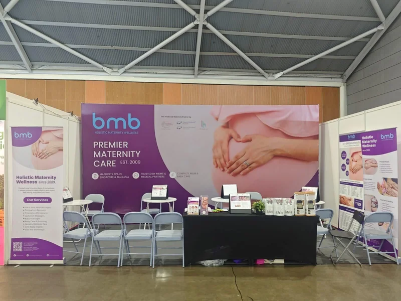 BMB booth at a previous baby fair — purple Premier Maternity Care backdrop, pull-up banners, and consultation chairs.